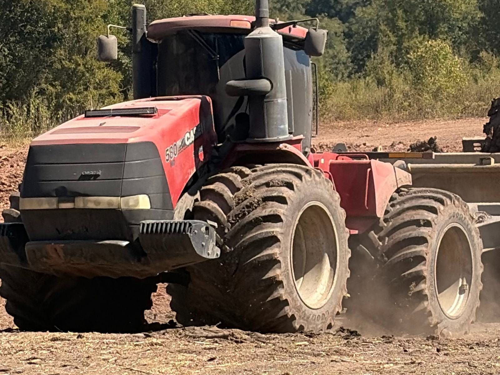 A Case IH Steiger 580 working a cleared site, dust coming off the tires.