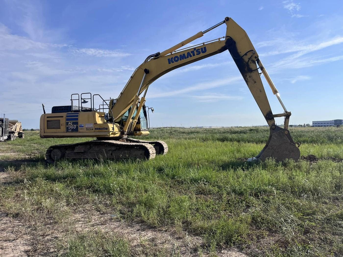 A Komatsu PC360 excavator on an open grass tract.