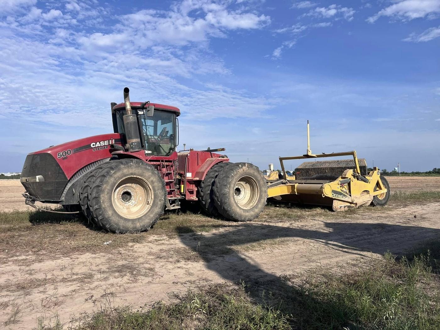 A Case IH Steiger 500 hooked to a pull scraper on a graded dirt lot.