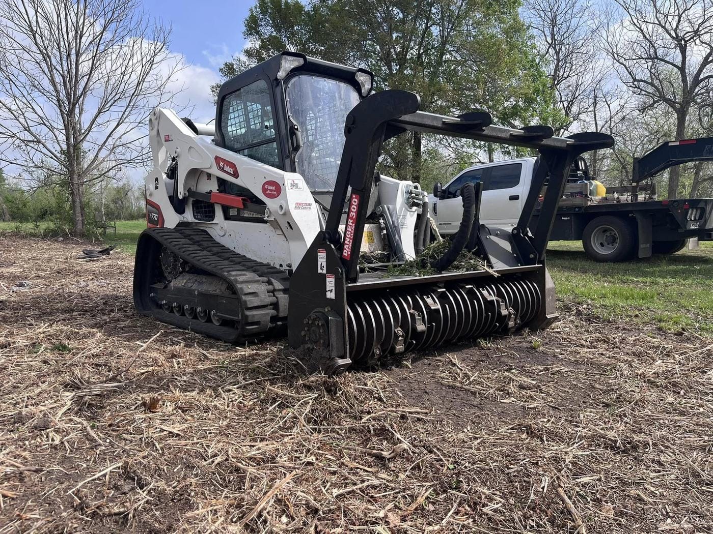 A Bobcat track loader with a forestry mulcher head, sitting in freshly mulched ground.