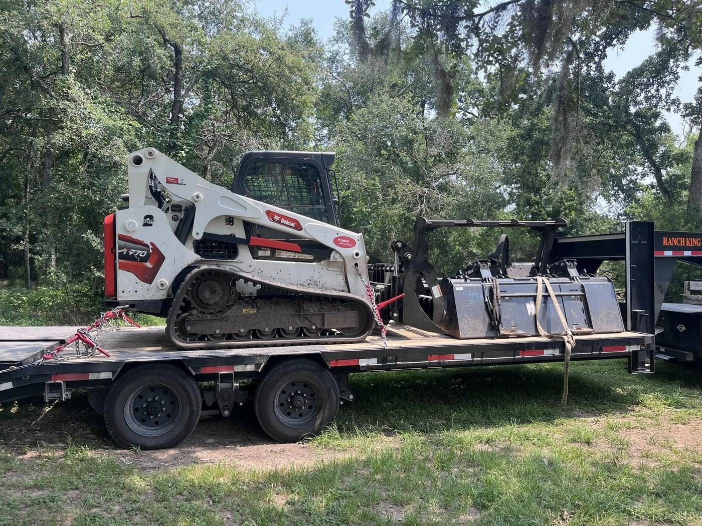 A Bobcat T770 track loader and a mulcher head loaded on a gooseneck trailer.